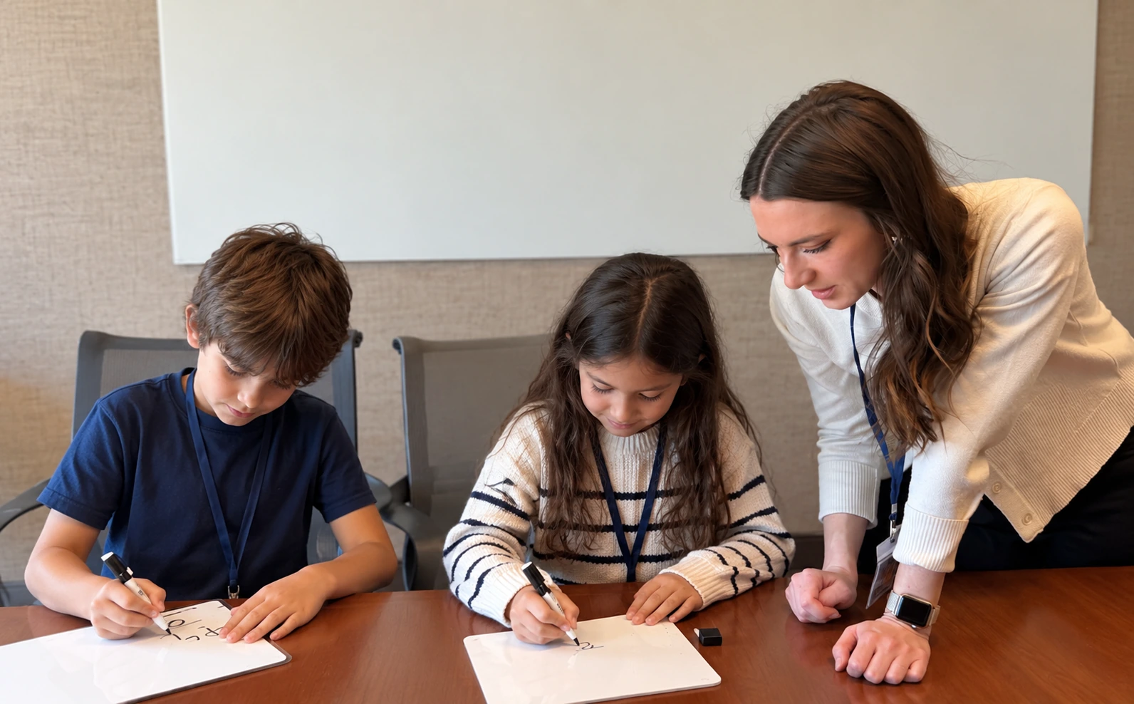 A learning coach supporting two students working on individual whiteboards