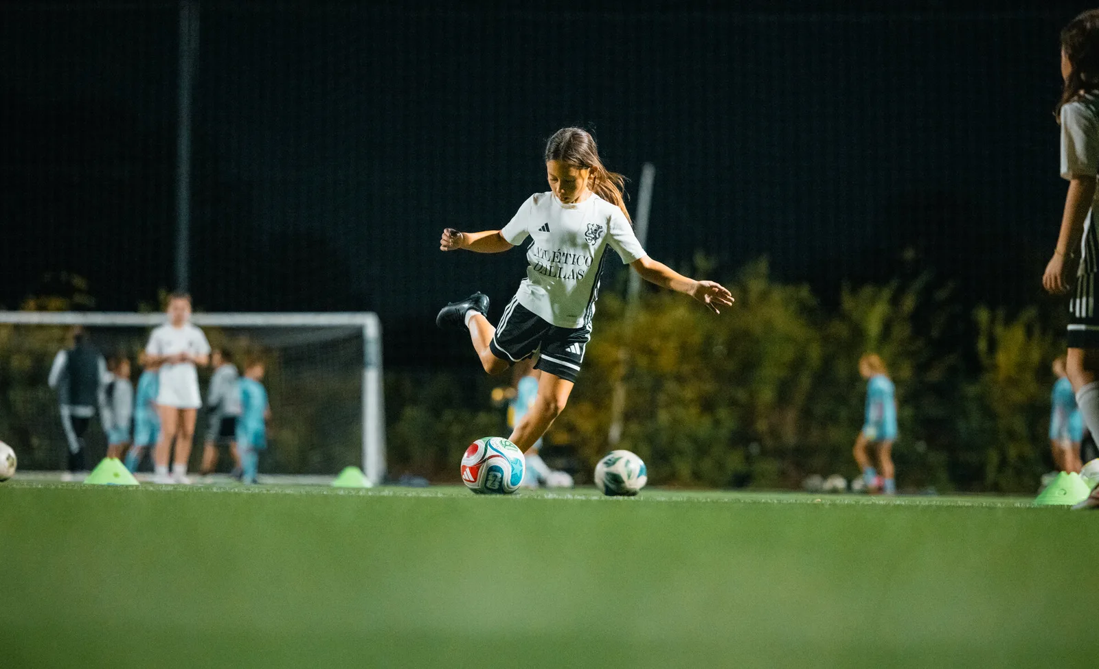 A young Atlético Dallas player practicing a shot during soccer training