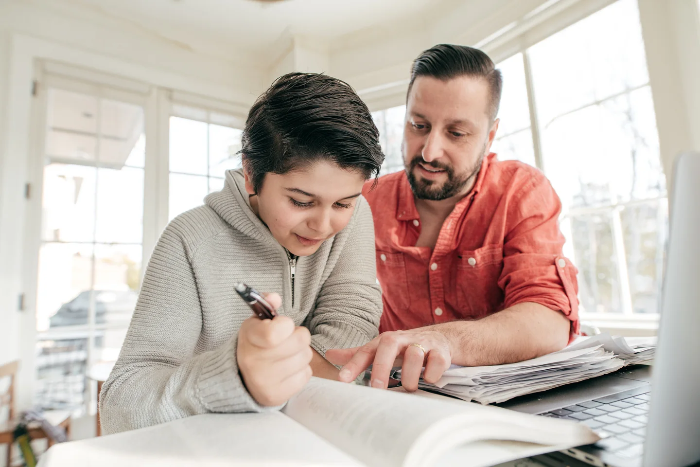A student reviewing coursework with an adult beside a laptop