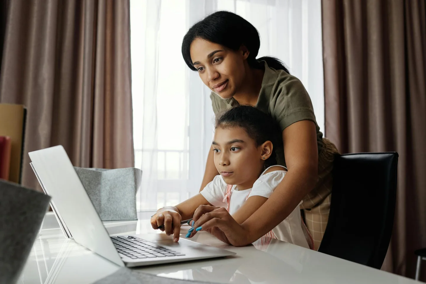 An adult and child working together on a laptop at home